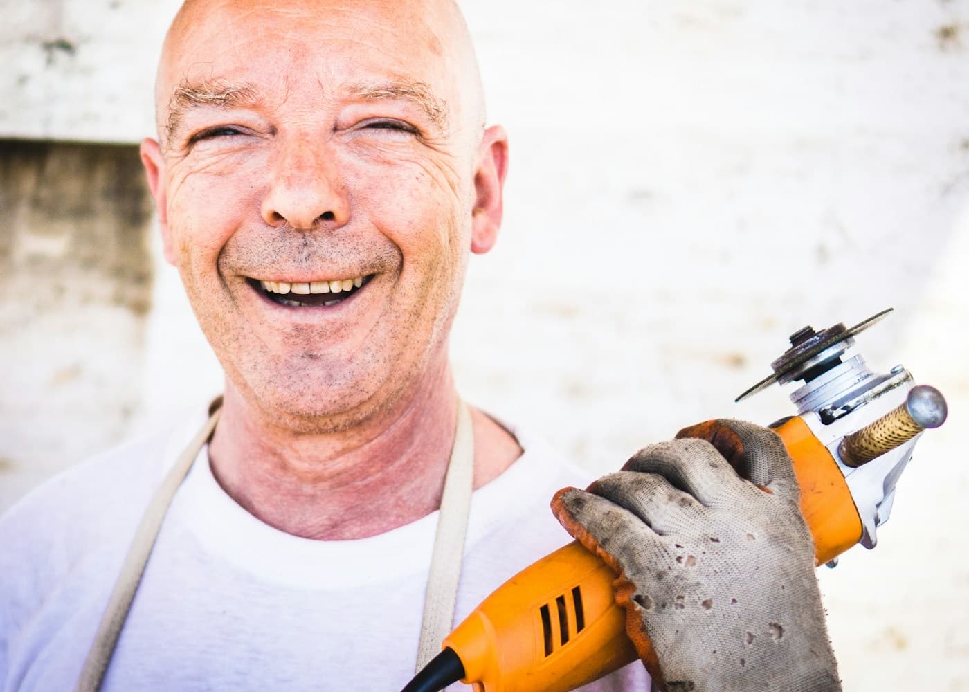 Homem sorrindo com uma ferramenta elétrica na mão