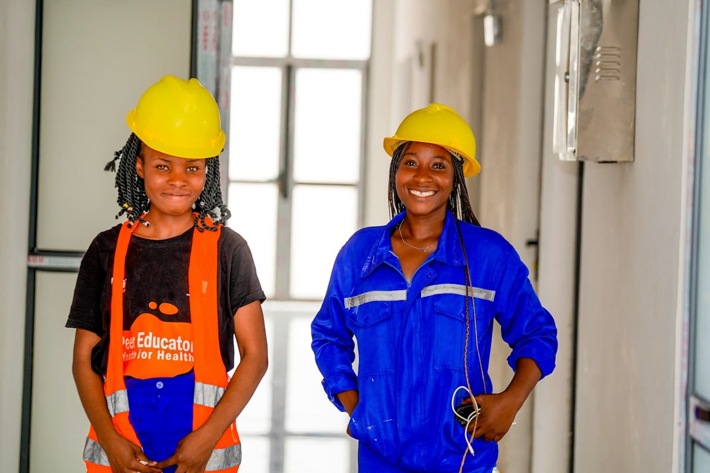 Duas trabalhadoras de capacete sorrindo no local de trabalho