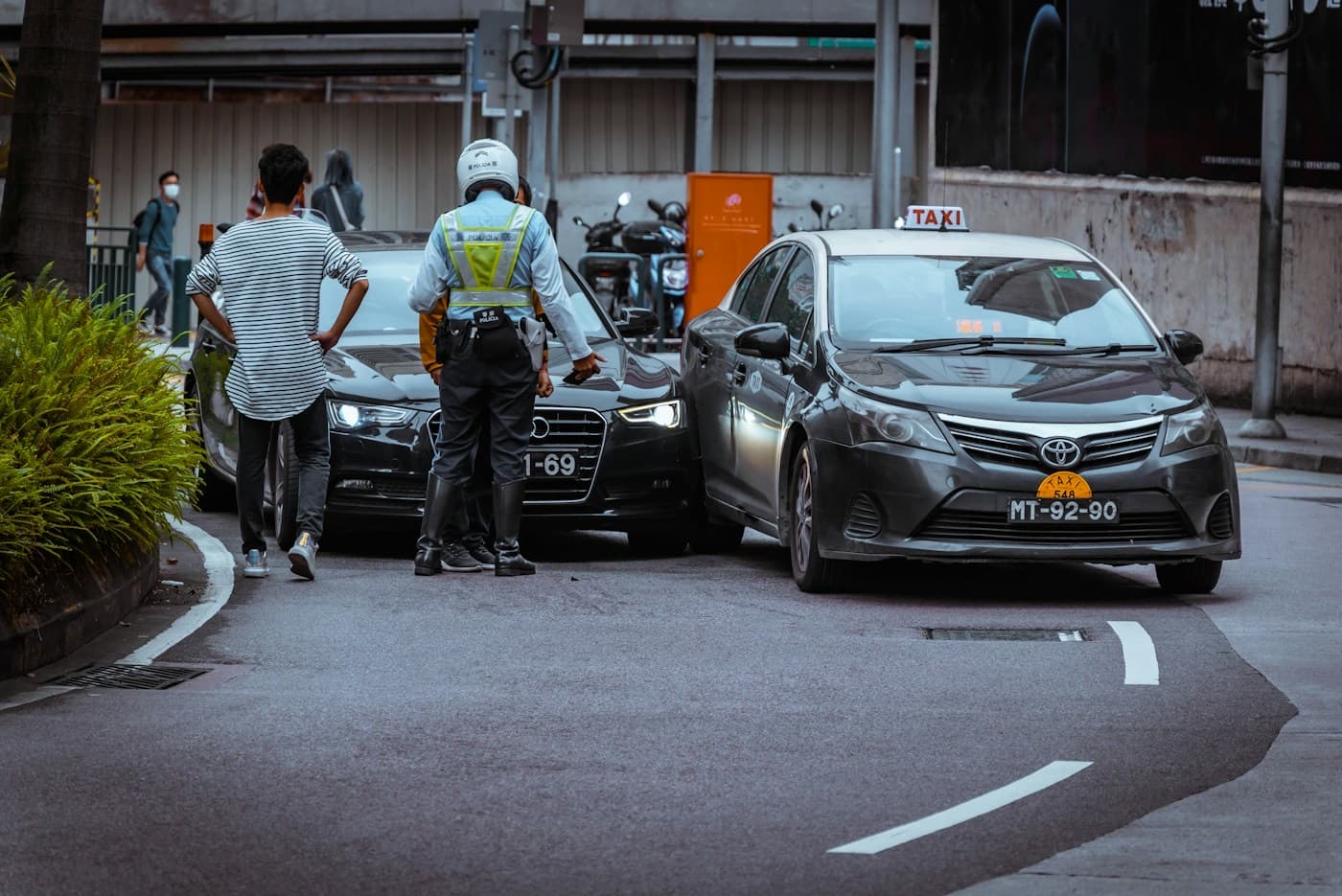 Motoristas conversando na rua ao lado de dois carros após uma batida leve
