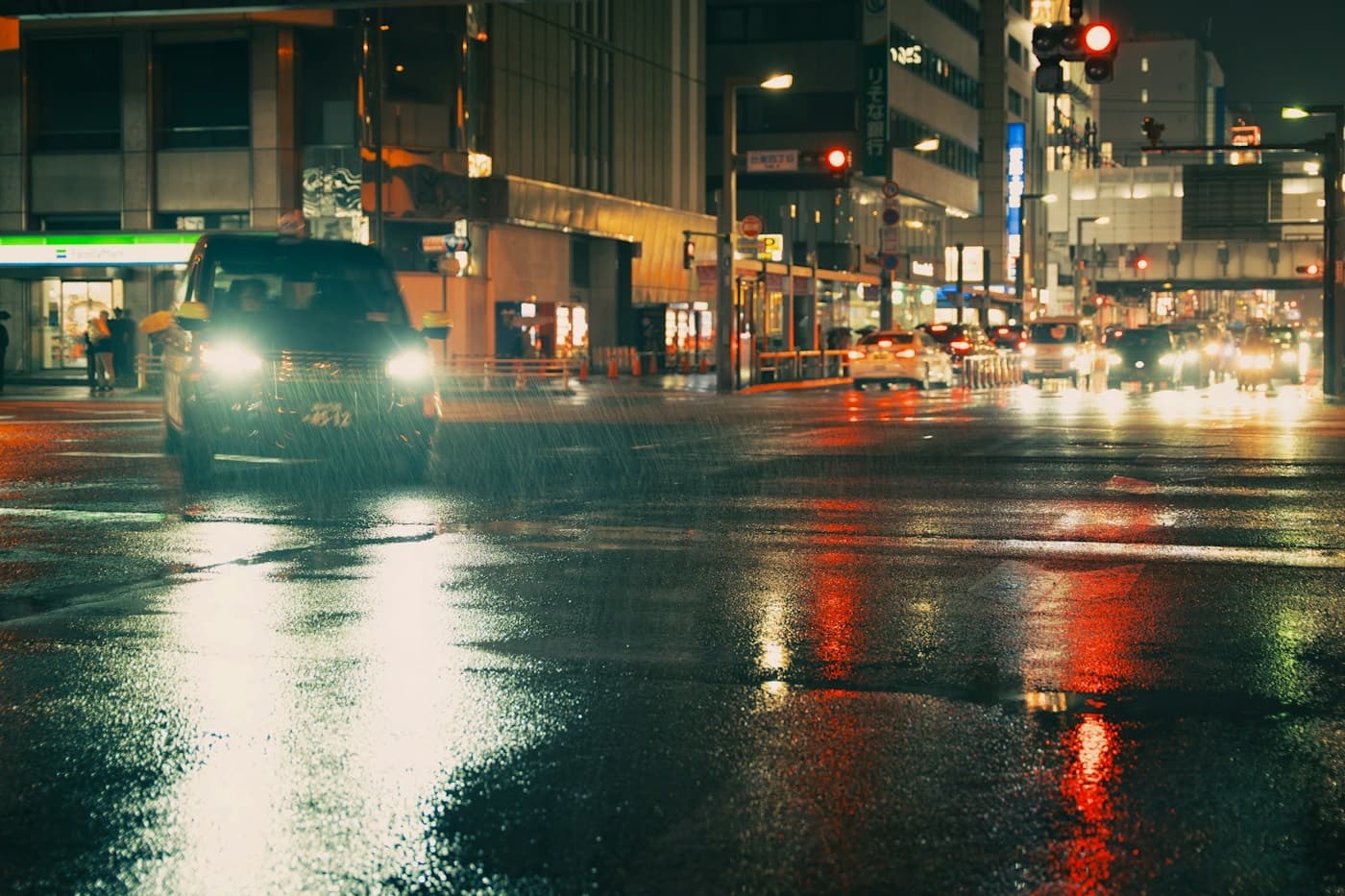 Rua molhada à noite com os faróis dos carros refletidos no asfalto