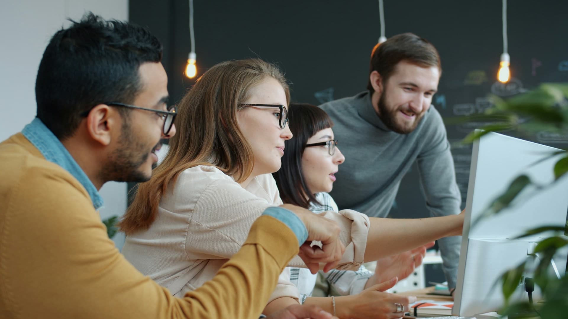 Equipe diversa reunida e sorrindo em torno de um computador