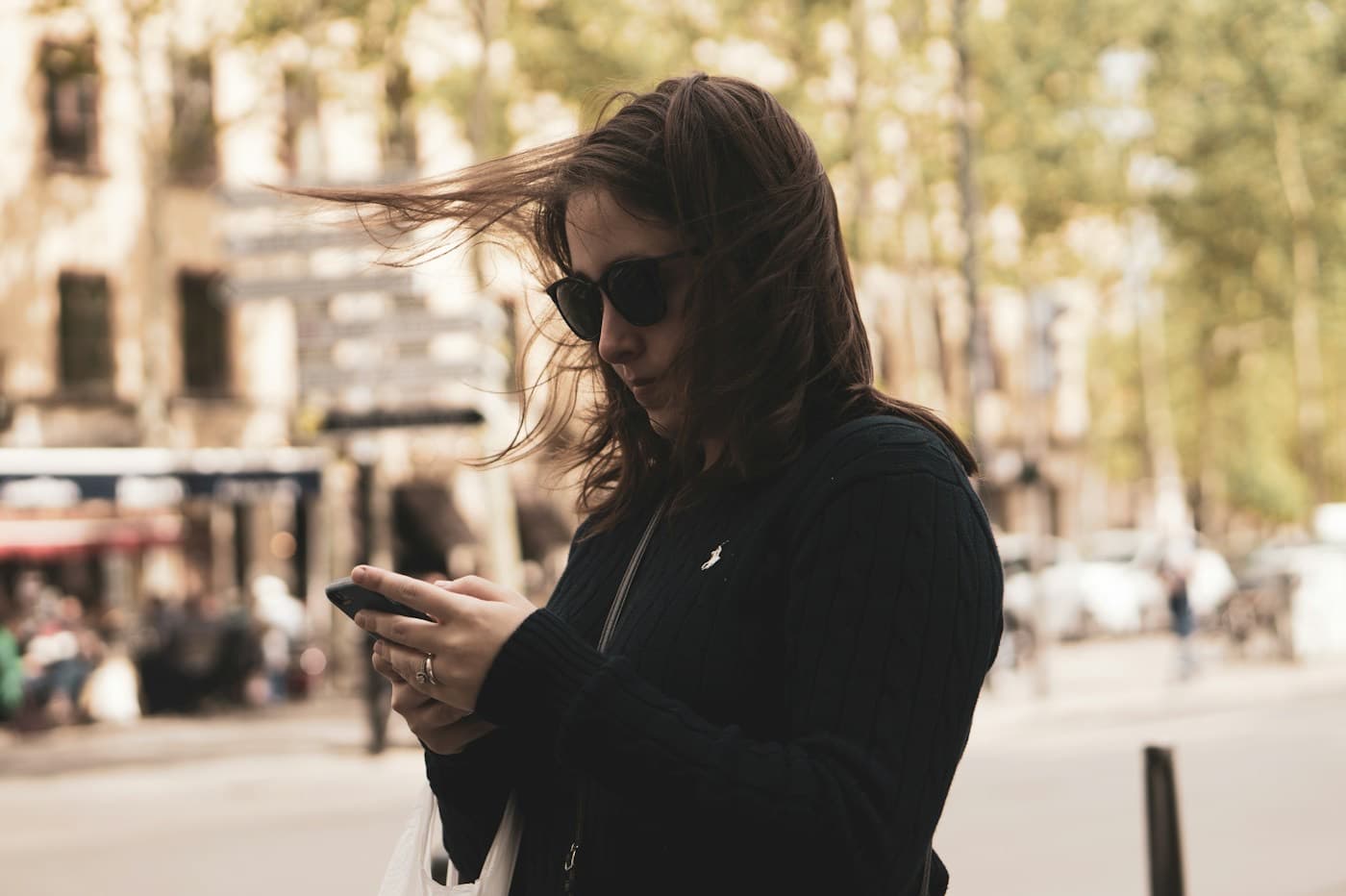 Mulher usando o celular enquanto caminha pela rua