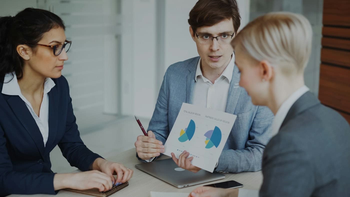 Três profissionais analisando gráficos em uma reunião