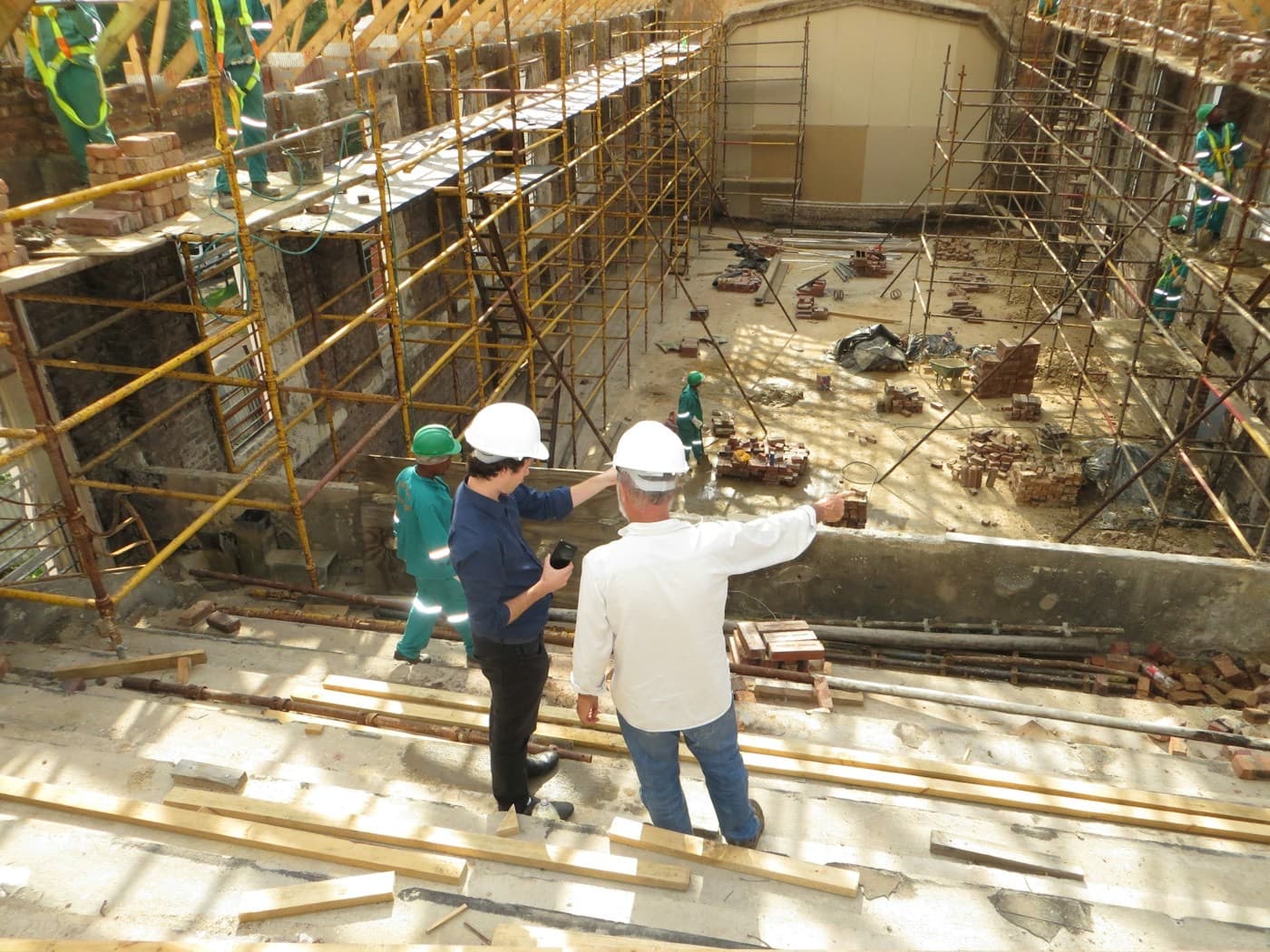 Dois engenheiros de capacete apontando para a estrutura de uma obra