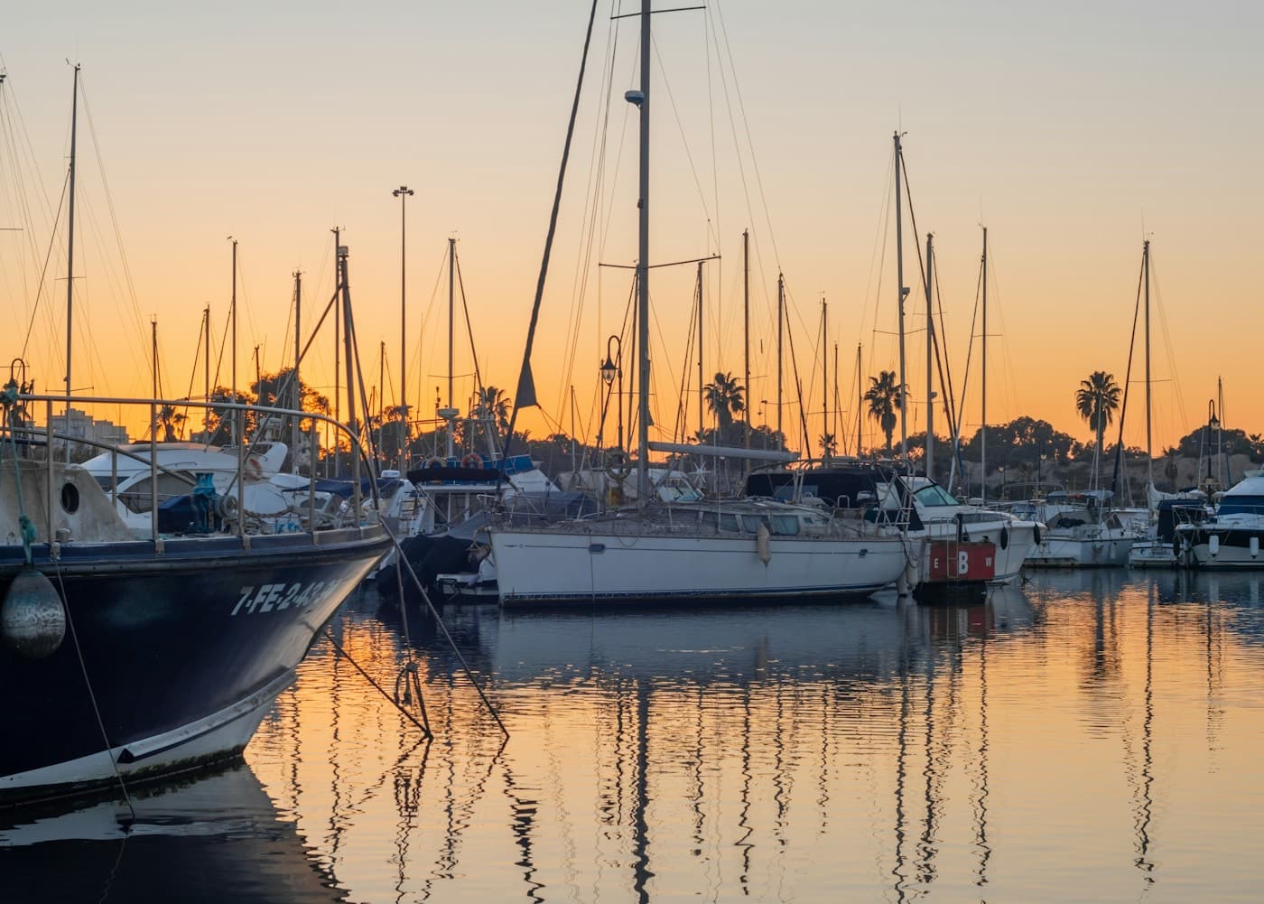 Barcos atracados em uma marina ao entardecer, refletidos na água calma