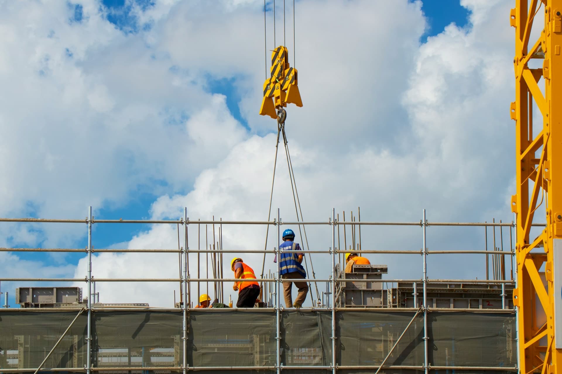 Equipe de operários no alto de uma obra, com grua ao fundo