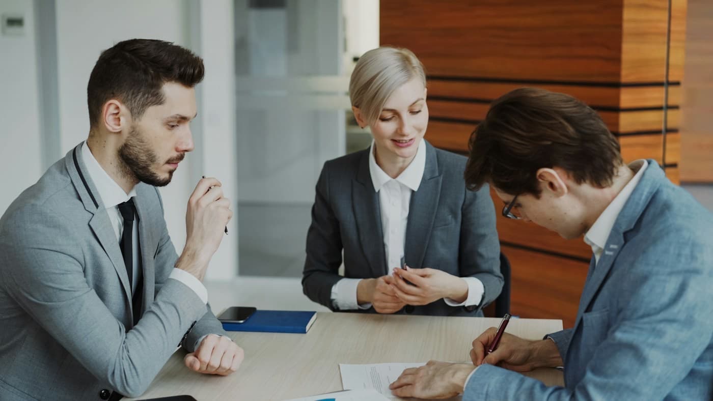 Profissionais assinando um documento em uma mesa de reunião