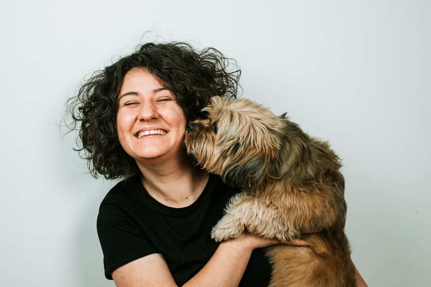 Tutora rindo enquanto abraça o seu cachorro