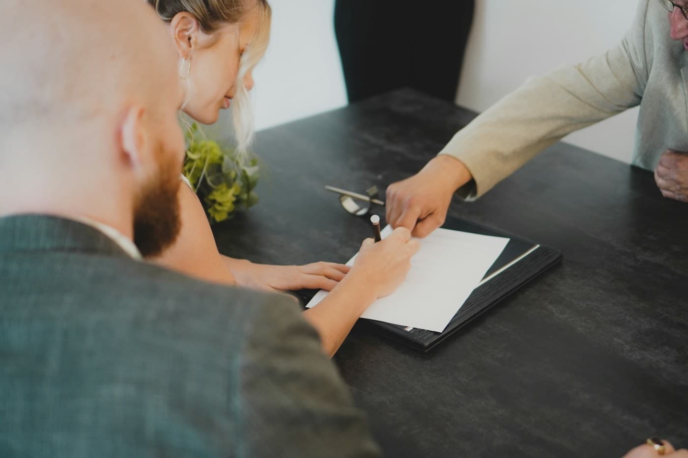 Casal assinando um documento à mesa com um consultor