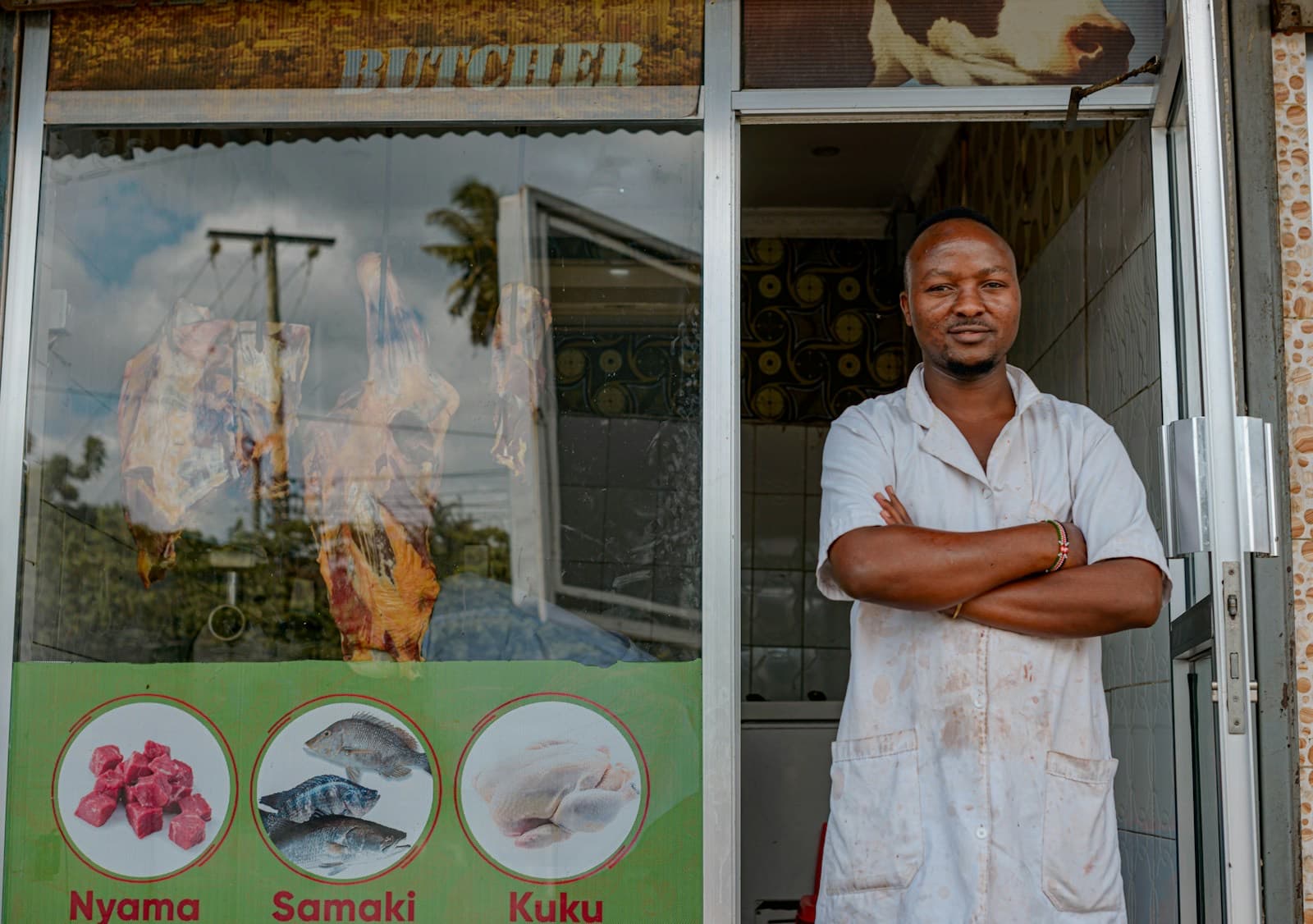 Comerciante de braços cruzados em frente à sua loja