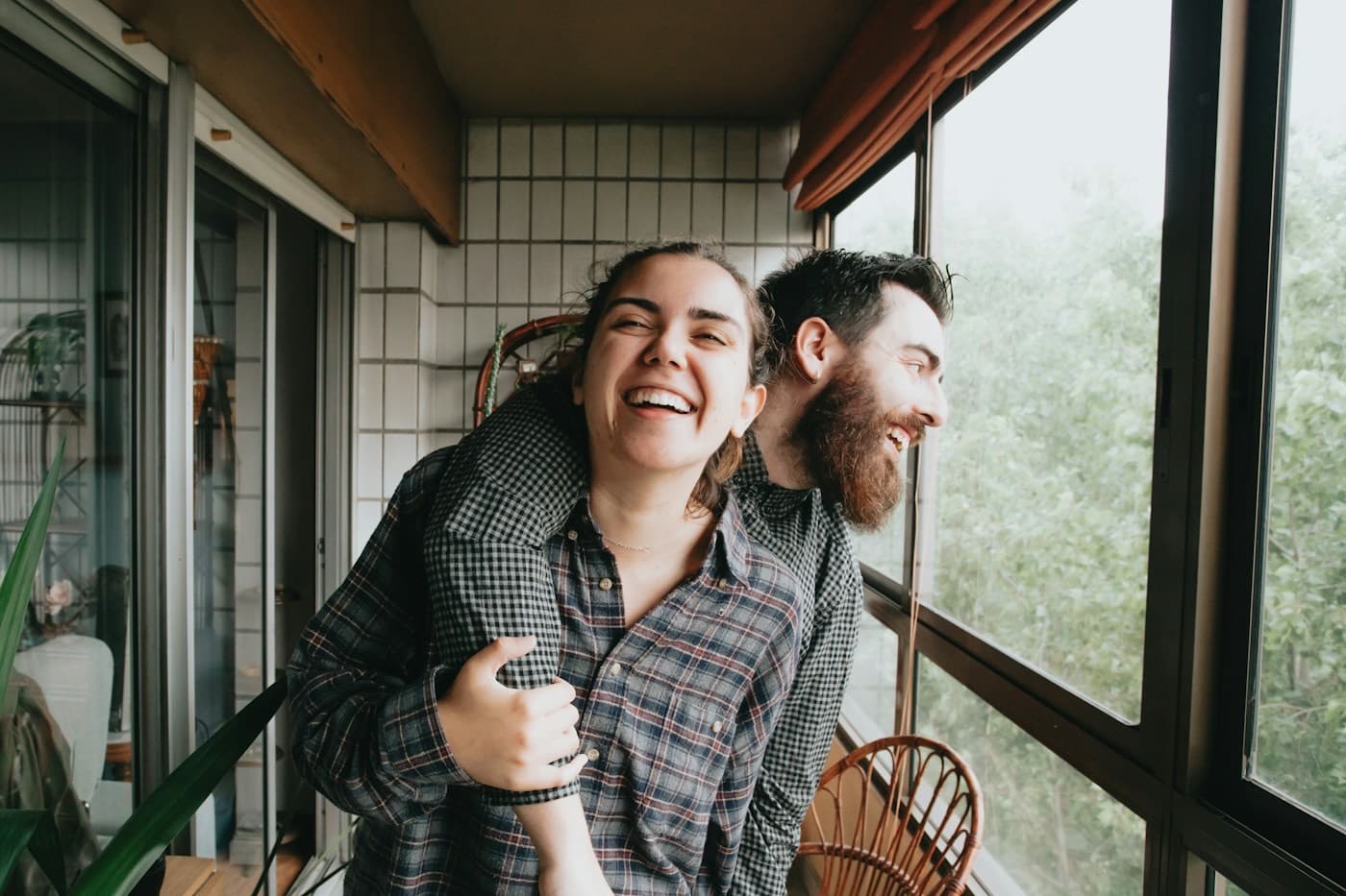 Casal rindo abraçado na varanda do apartamento