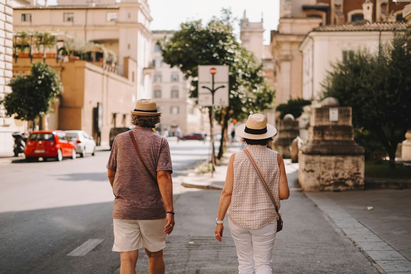 Casal de chapéu caminhando por uma rua de uma cidade europeia